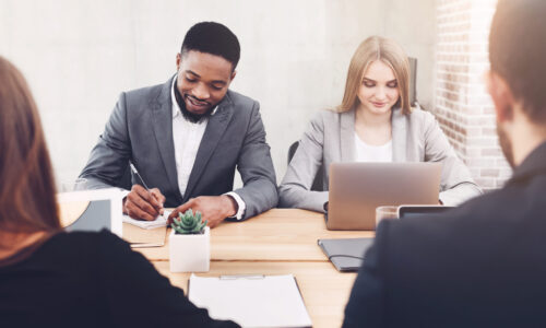 Diverse business people working together, using laptop and writing notes in office